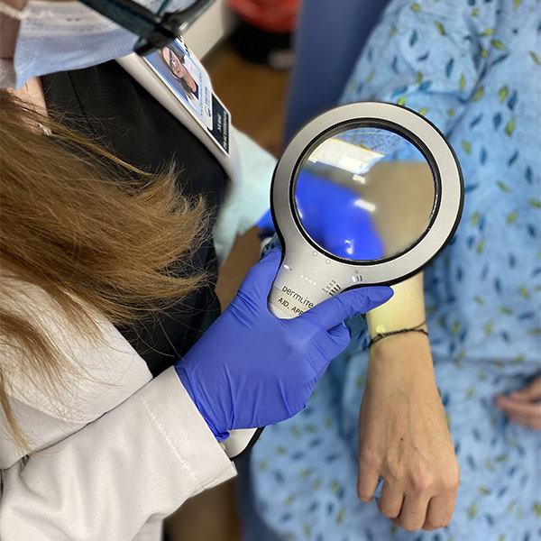 Doctor using magnifying glass on patients arm